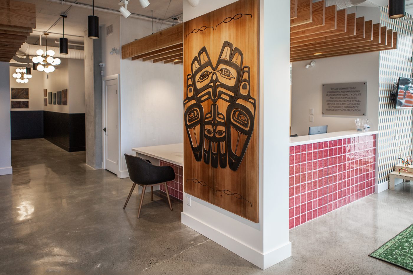Hollyburn Eye Clinic — reception with Indigenous carved cedar panel, cedar beam ceiling and pink tile millwork, North Vancouver