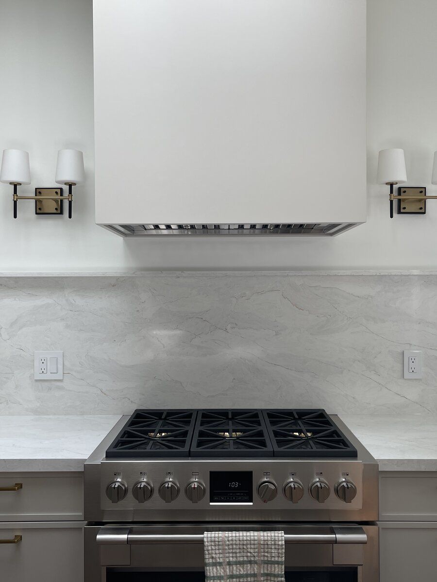 Hoskins Road — custom range alcove with marble slab backsplash, flanking sconces, and Fulgor professional range