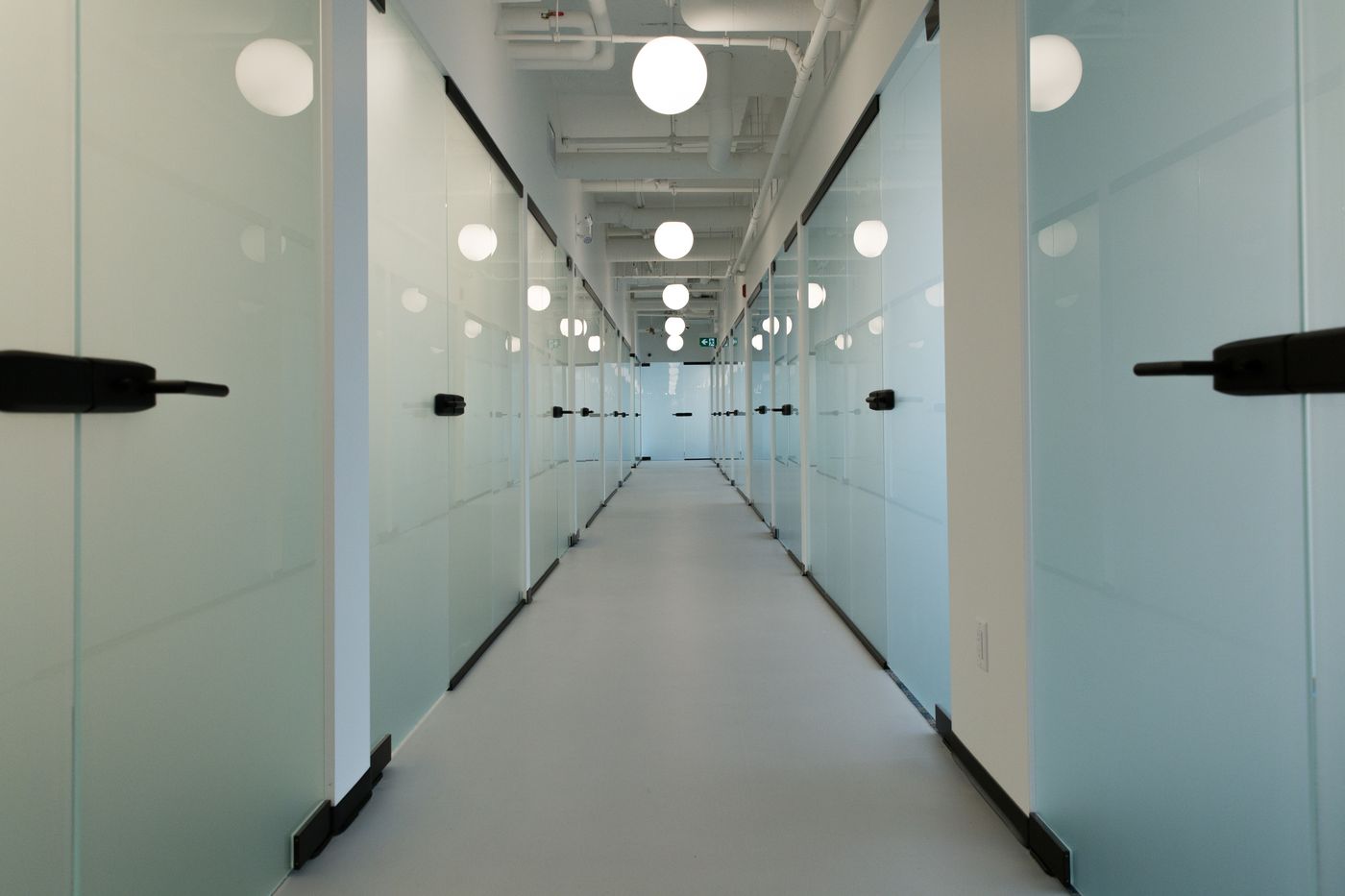 West Quay — glass office corridor with globe pendants, North Vancouver